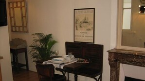 Un coin repas avec une table en bois, deux chaises, une plante en pot et un tableau encadré au mur.