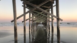 A wooden pier extending into the ocean at sunset.
