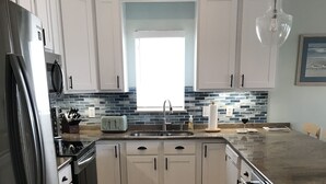 A modern kitchen with white cabinets, a stainless steel refrigerator, a microwave, and a dishwasher.