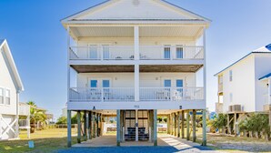 Een tweelaags gebouw aan het strand, met een balkon op elke verdieping, genummerd 1213 en 1215, en een overdekte ingang.