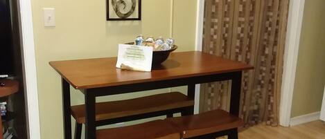 A dining table with benches, a decorative wall piece, and a bowl of items on the table.