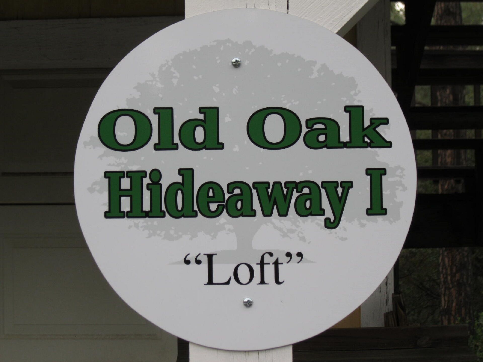 En rund skylt med texten ”Old Oak Hideaway I” och ”Loft”, vilket anger ett specifikt rum eller område.