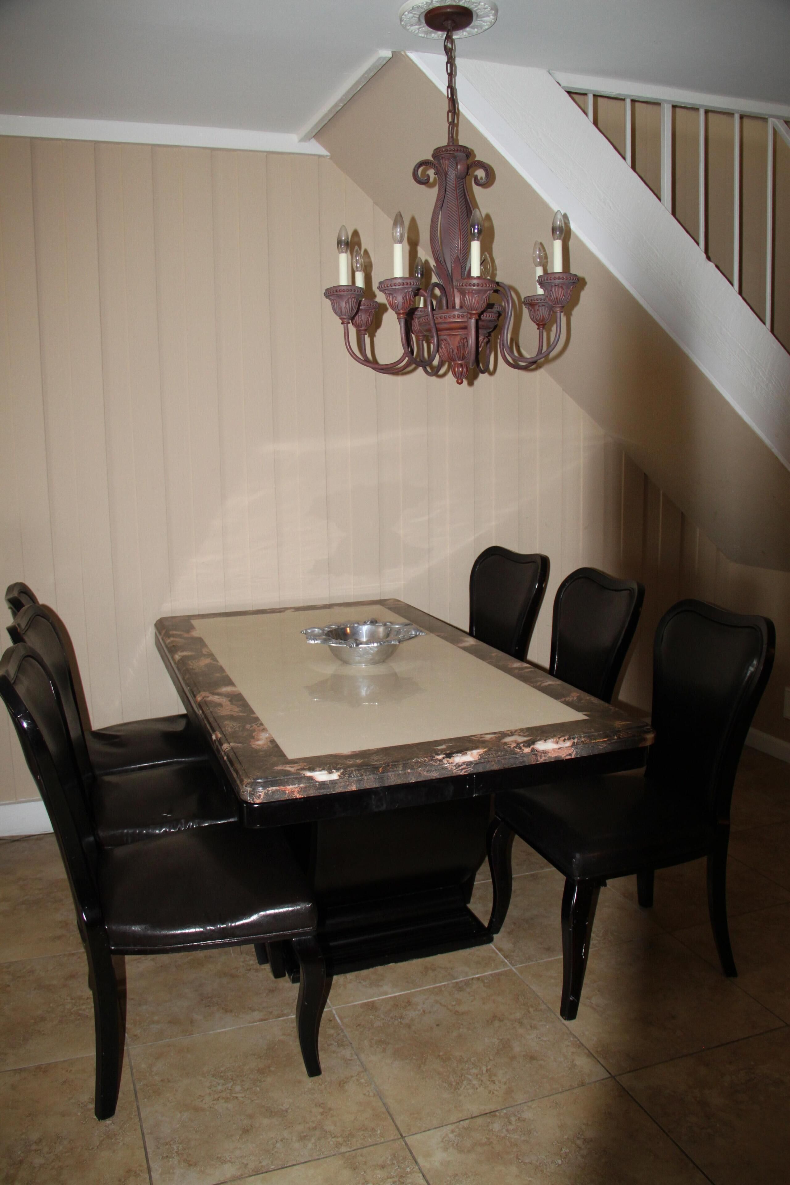 A dining area with a rectangular table, four chairs, and a chandelier.