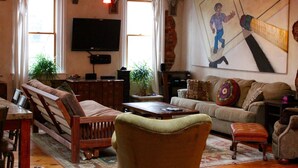 Un salon comprenant un canapé, un fauteuil, une table basse et un téléviseur fixé au mur.