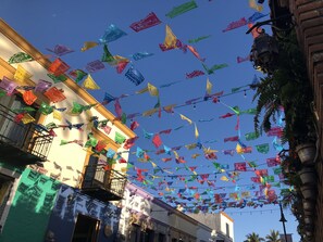 Une rue où pendent des guirlandes de fanions colorés.