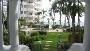 Vista de resort com piscina, palmeiras e um prédio com varandas.