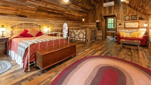 Ein rustikaler Holzraum mit einem Bett, einer Bank, einem roten Sofa und einem gemusterten Teppich.