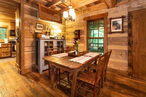 A rustic wooden interior with a dining table set for four, surrounded by wooden chairs.