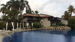 A resort with a swimming pool, palm trees, and a building with a tiled roof. - <br>Private beach Exclusive Beach Zihuatanejo, direct access La Ropa RVILLAS SOL (ZIHUATANEJO)