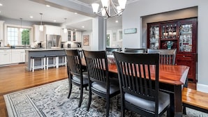 A spacious kitchen with modern appliances, a dining area with a wooden table and chairs, and a decorative cabinet with glass doors.