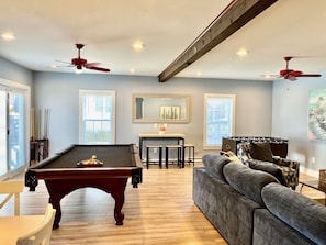 Relax in this stylish living area with a pool table, comfortable sofa, and dining table.