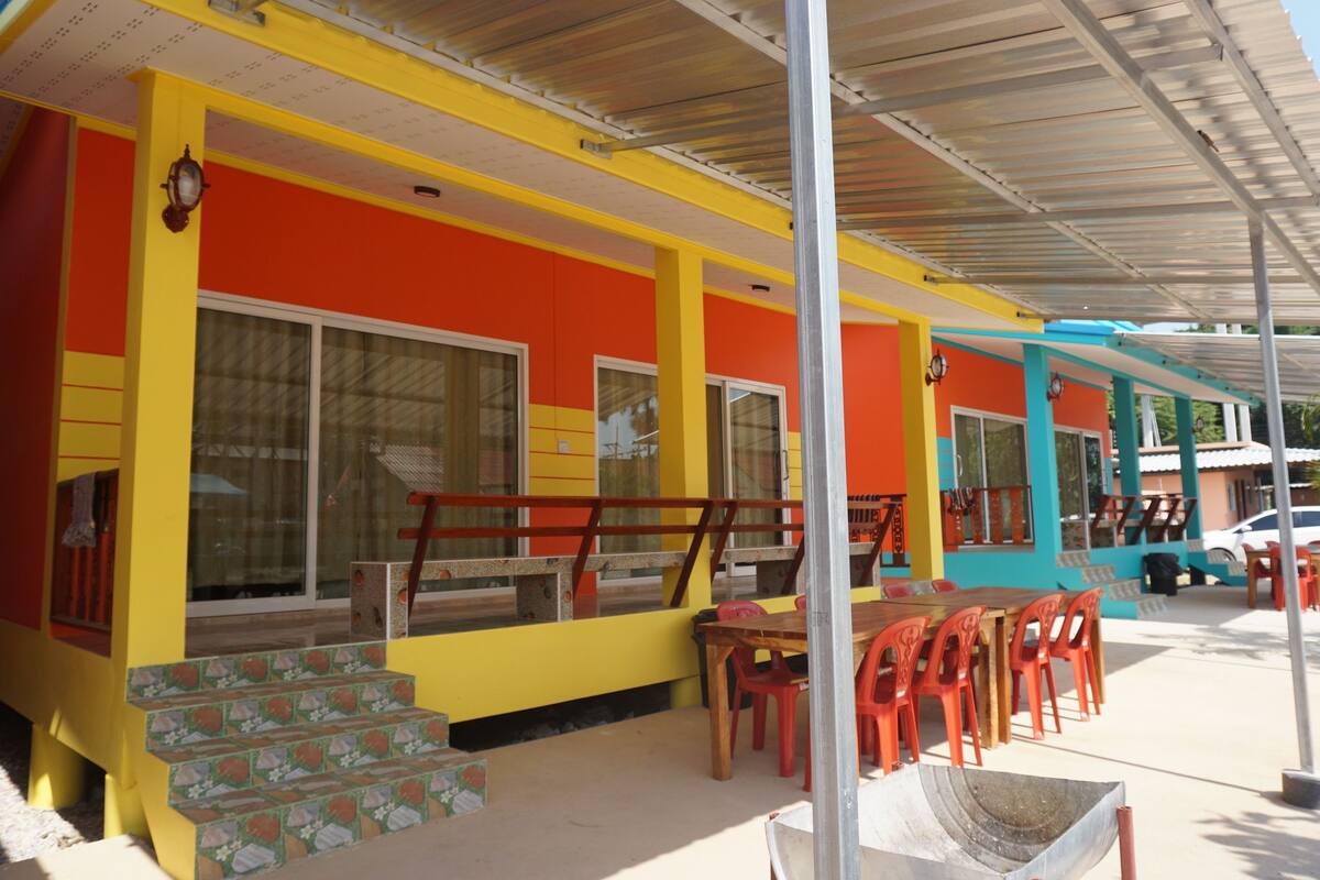 A colorful building with a covered outdoor seating area and steps leading to the entrance.