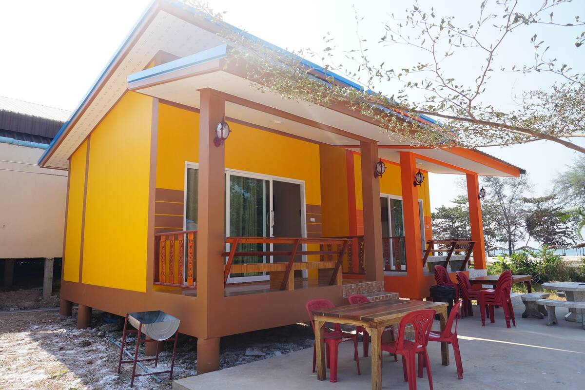 A yellow building with a balcony and outdoor seating area.