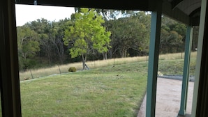 Un espacio al aire libre cubierto con un sendero de ladrillo que conduce a un campo cubierto de césped y árboles al fondo.