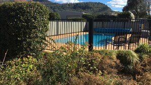 A swimming pool surrounded by a black fence, with a mountain backdrop and clear sky. - Farm Escape - Spacious Cottage in Kangaroo Valley (Kangaroo Valley)
