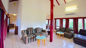 Uma sala de estar ampla com sofás listrados, uma mesa de centro redonda e um pilar vermelho.