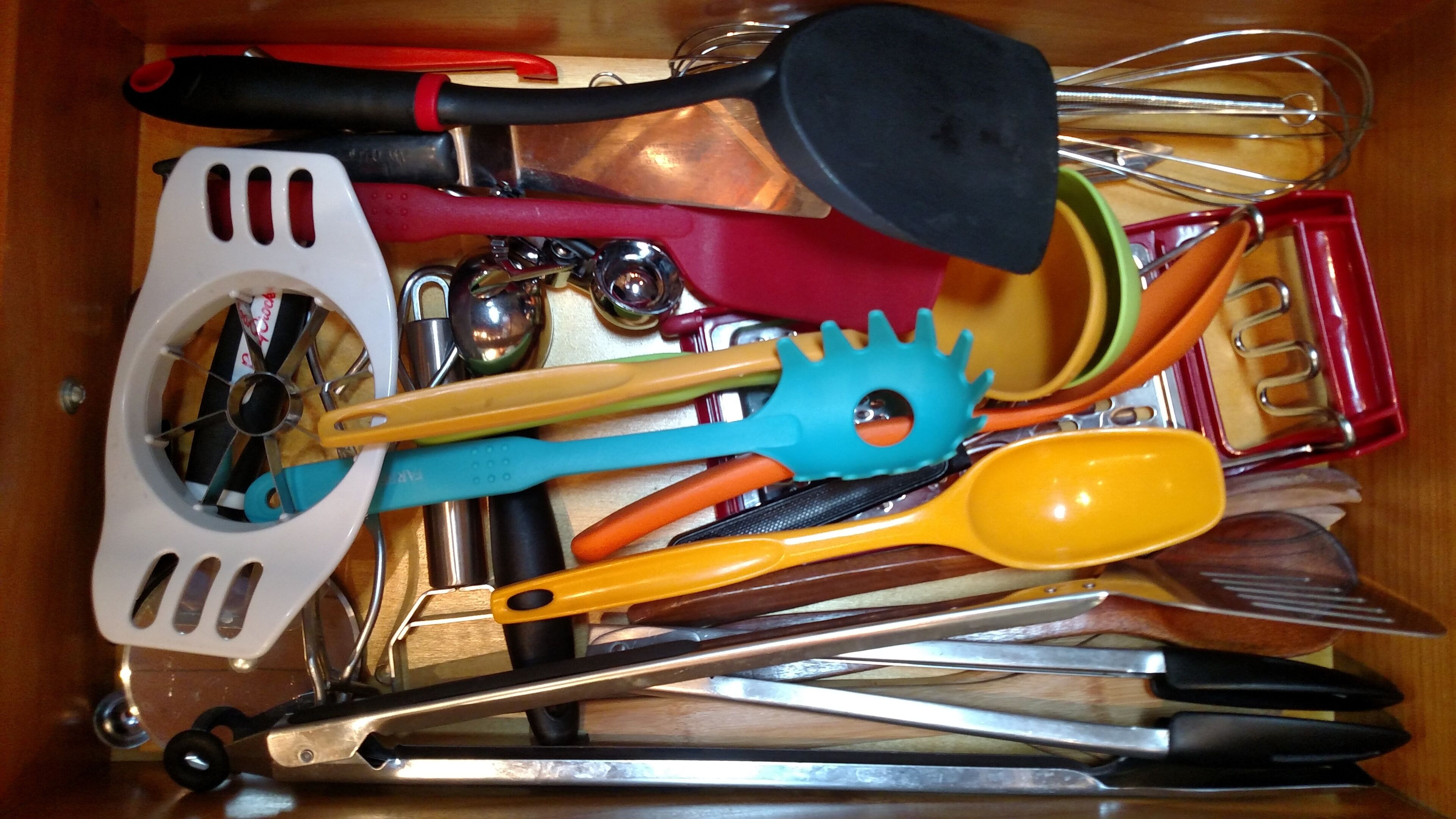 A drawer filled with various kitchen utensils including spatulas, whisks, and tongs.