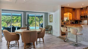 A modern kitchen with wooden cabinets, a stainless steel refrigerator, and a bar area with stools. - Renovated 3BR/2BA with large heated saltwater pool & tiki bar (Oakland Park)
