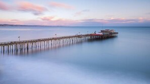 A pier extending into calm waters with a sunset in the background.