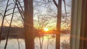 A view of a sunset over a lake with trees and a wooden staircase leading down to the water. - Sweet By and By... Your Escape to the Beauty of Smith Mountain Lake (Huddleston)