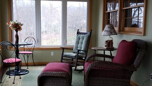 A cozy room with a large window, wicker furniture, and a lamp. - Sweet By and By... Your Escape to the Beauty of Smith Mountain Lake (Huddleston)