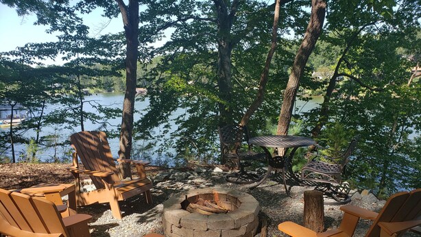 A lakeside seating area with Adirondack chairs and a fire pit. - Sweet By and By... Your Escape to the Beauty of Smith Mountain Lake (Huddleston)