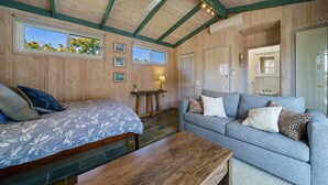 Una habitación acogedora con una cama, un sofá, una mesa de madera y un ventilador de techo.