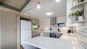 Una cocina moderna con una isla grande, armarios blancos y vistas al exterior.