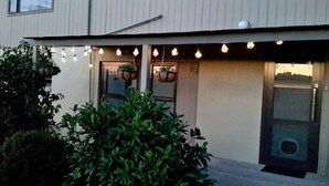Un bâtiment moderne doté d’un toit plat, d’une porte d’entrée et d’un petit porche agrémenté de guirlandes lumineuses.