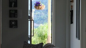 Une chambre avec un lit, une fenêtre donnant sur un paysage verdoyant et des horloges fixées au mur.