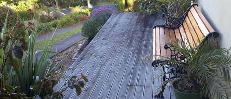 Una terraza de madera con un banco y plantas en macetas.