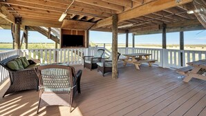 A covered outdoor deck with wicker furniture, a flat-screen TV, and a white railing. - Reel'em In Lodge - A Reel Fisherman Lodge! (St Bernard)