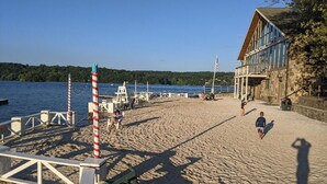 Ein Strand mit einem Holzgebäude, einem Rettungsturm und einer Flagge.