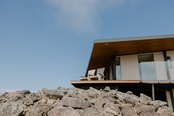A modern building with a flat roof and a balcony with two chairs.