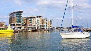 A marina with a white sailboat and a yellow boat docked.