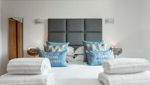 A modern bedroom with a large bed, two bedside tables, and a headboard.
