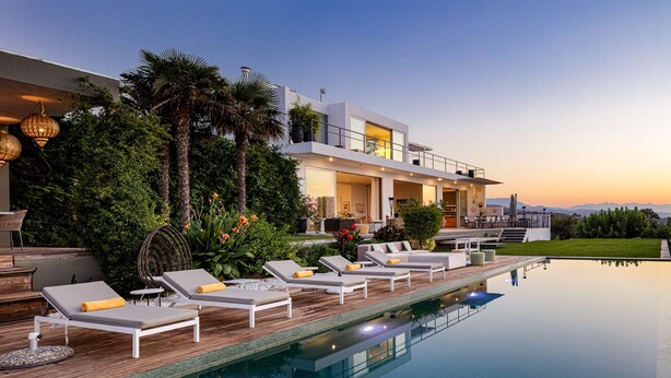 Un área moderna junto a la piscina con sillones de descanso y vista despejada.