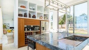 A modern kitchen with a marble countertop, built-in wine storage, and a large window offering a view of the outdoors. - Villa Amnalys - Sea View, Gardens & Spa by etouri (Rethymno)