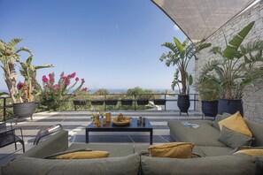 A terrace with outdoor seating, potted plants, and a view of the landscape.