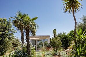 A modern house with a glass facade, surrounded by lush greenery and palm trees. - Villa Amnalys - Sea View, Gardens & Spa by etouri (Rethymno)
