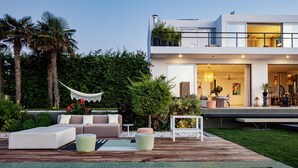 Una casa moderna con piscina, mobiliario exterior y abundante vegetación.