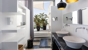 Un baño moderno con dos lavamanos, un espejo grande y plantas en macetas.