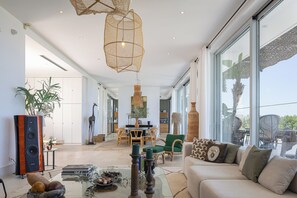 Ein geräumiger Wohnbereich mit großem Fenster, einer Couch, einem Esstisch und verschiedenen dekorativen Elementen.