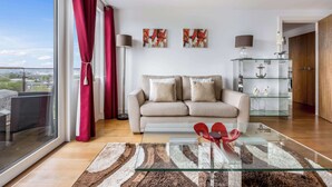 A modern living room with a sofa, glass coffee table, and artwork on the wall. - Tides - Poole Town Views, On-site Parking (Poole)