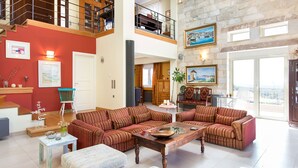 A spacious living area with a high ceiling, a staircase, and a balcony with a view. - Spacious villa with full privacy & nature views! (Rethymno)