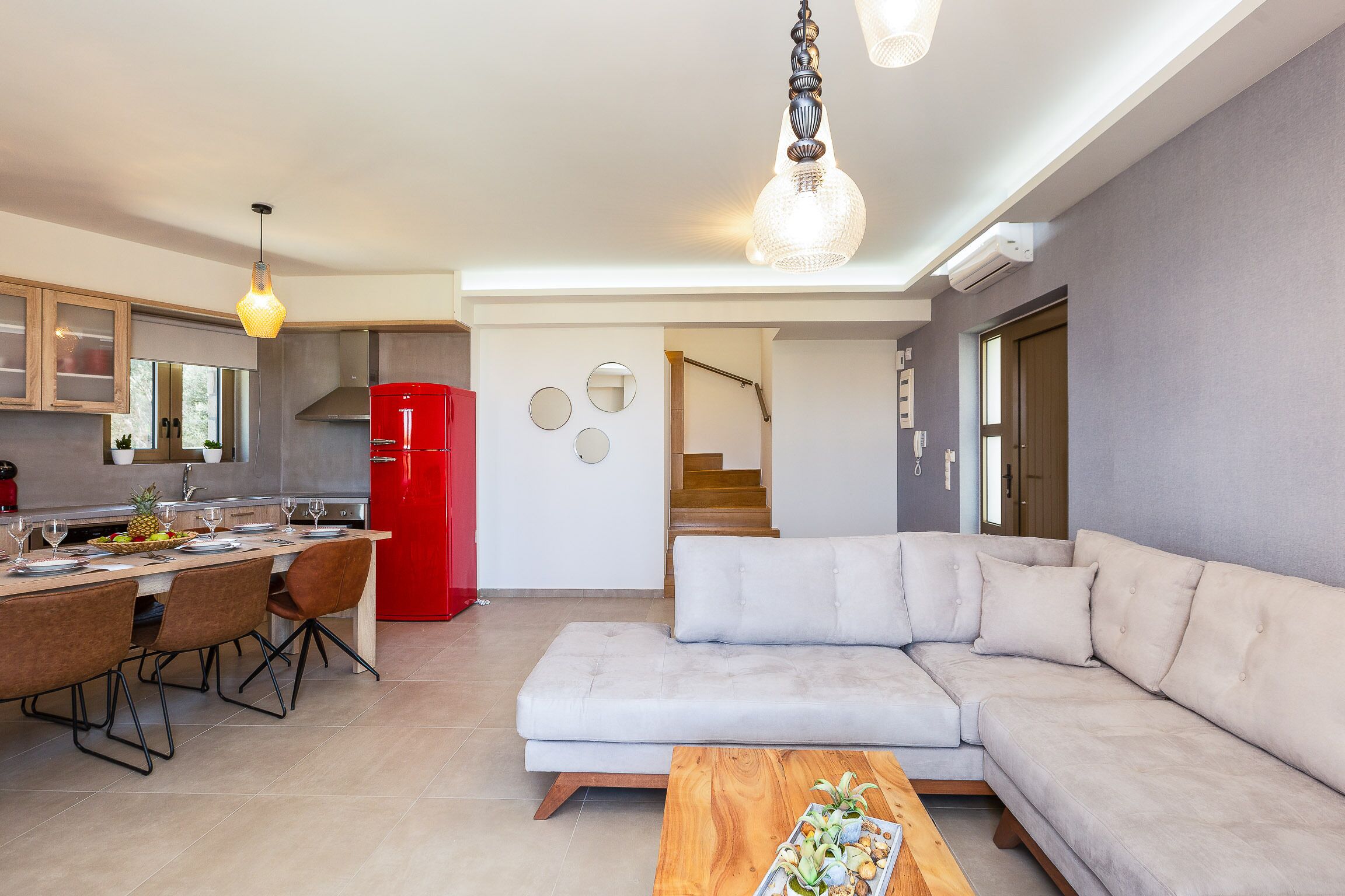 Una cocina moderna con comedor, una sala de estar con sofá y una escalera que lleva a otro nivel.