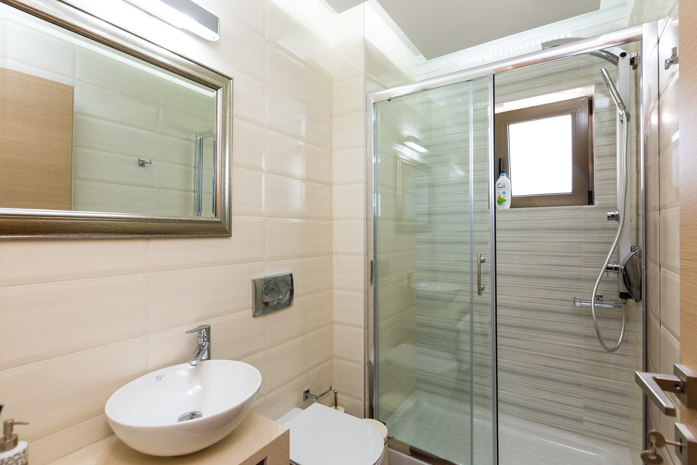 A modern bathroom with a glass shower enclosure, a white sink, and a large mirror.