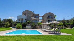 Ein zweistöckiges Steinhaus mit Swimmingpool, Sitzgelegenheiten im Freien und einem gepflegten Garten.