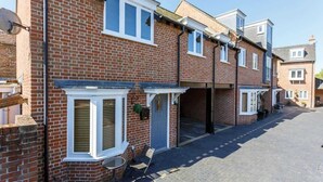 A row of terraced houses with brick facades, white window frames, and a paved driveway. - Magnolia House - Townhouse in Old Town Poole (Poole)