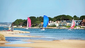 A coastal scene with sailboats on the water, a sandy beach, and houses in the background. - Magnolia House - Townhouse in Old Town Poole (Poole)